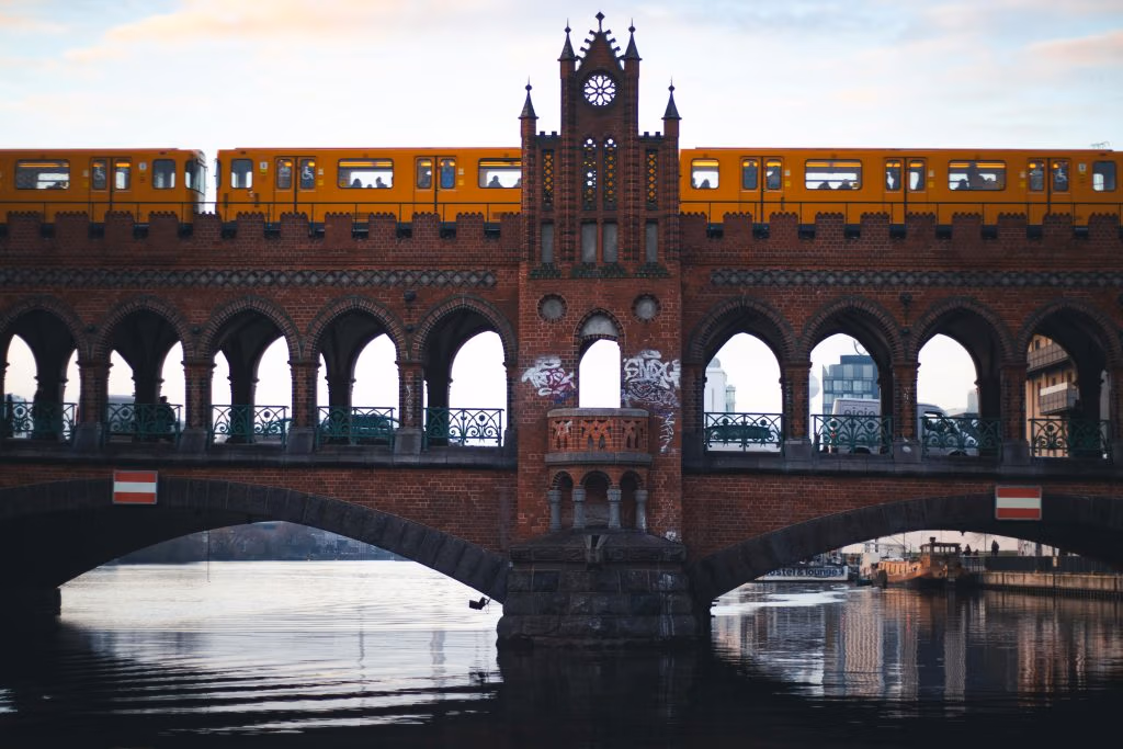 Urban scene of the yellow train crossing Berlin's historic Oberbaum Bridge over the river.