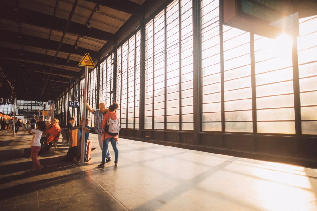 A vibrant moment at a Berlin train station with warm sunlight streaming through large glass windows.